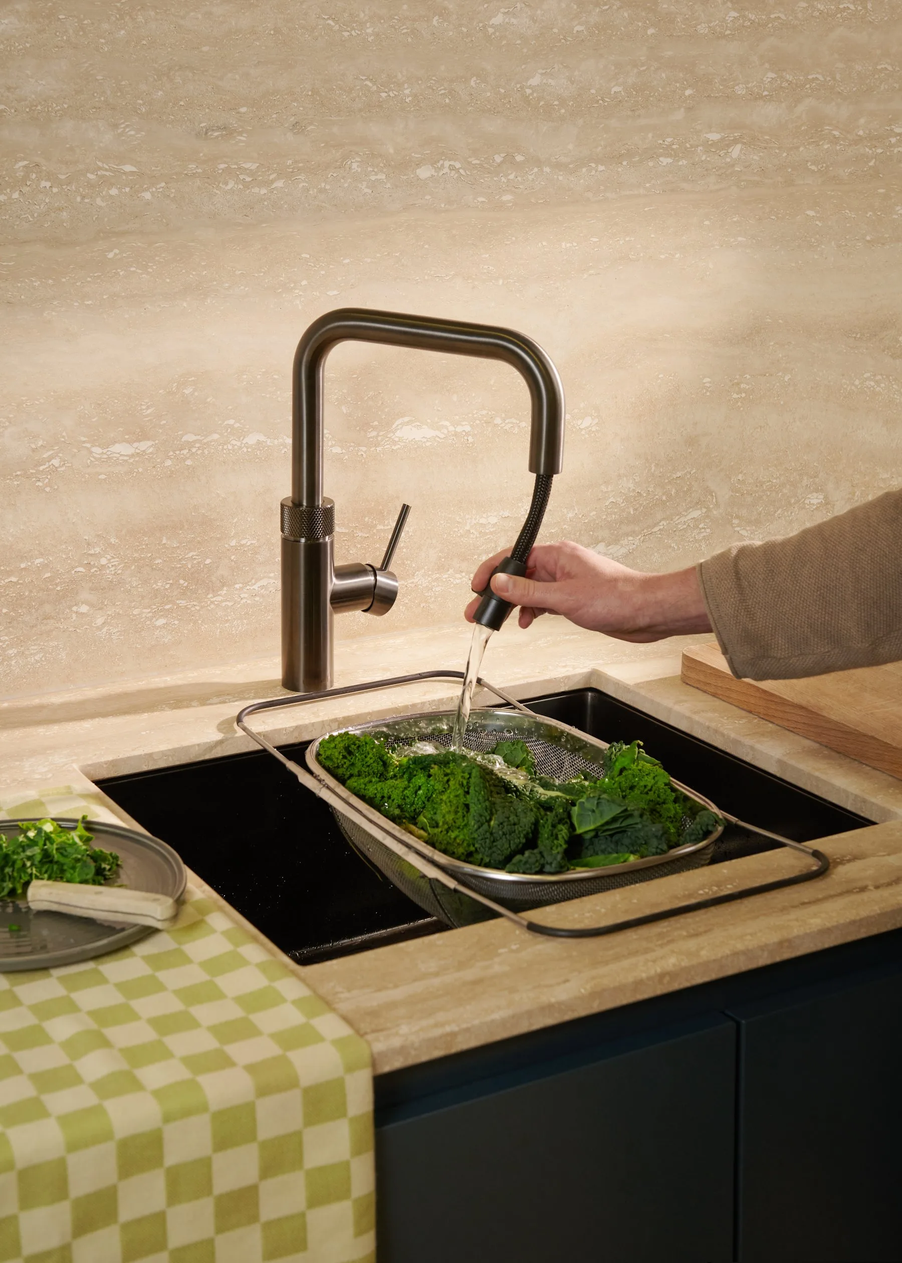 Quooker Flex Square tap in gunmetal with its pull-out hose rinsing greens over a sink