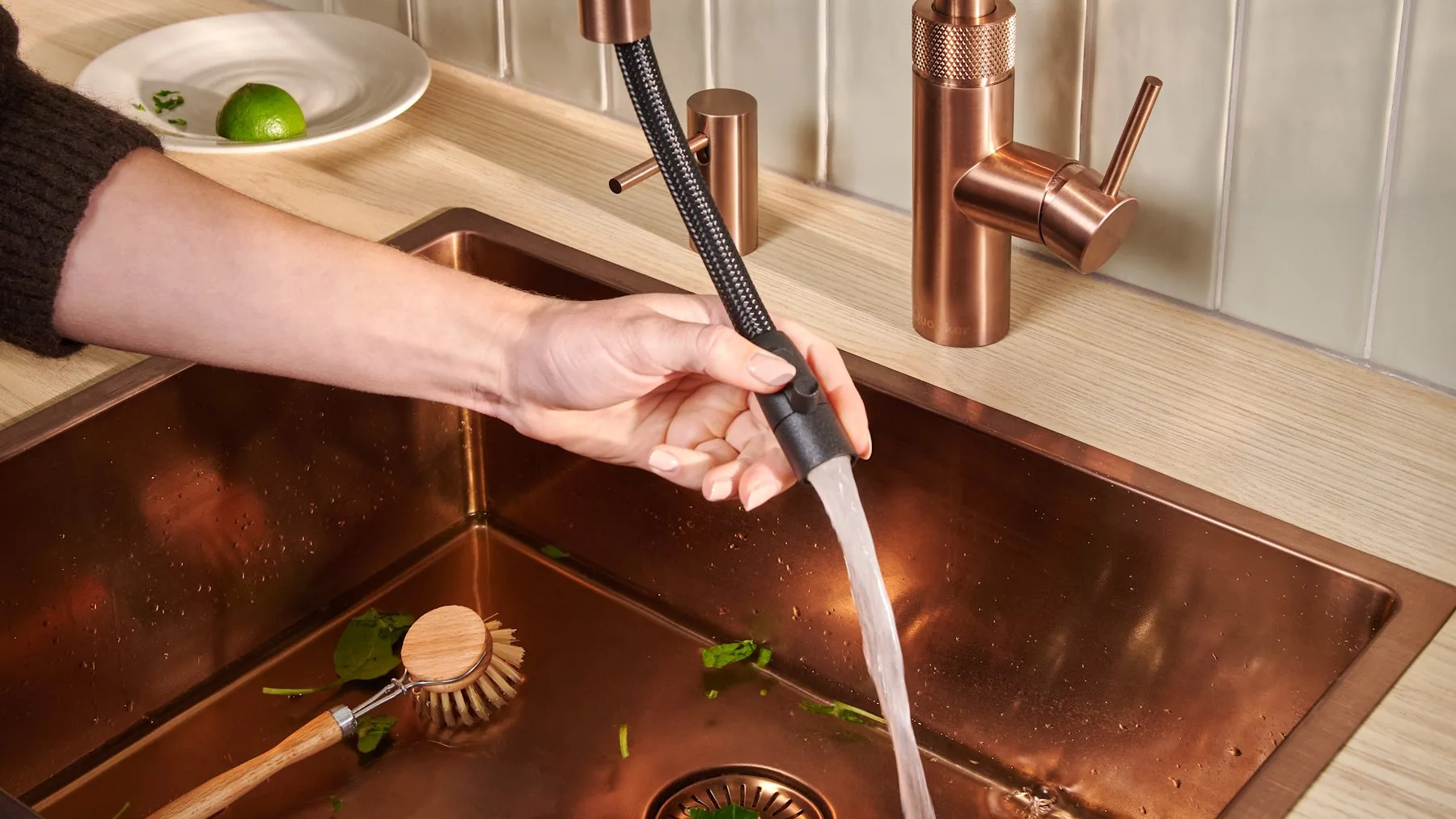 Quooker Flex pull-out hose in rose copper rinsing a copper sink