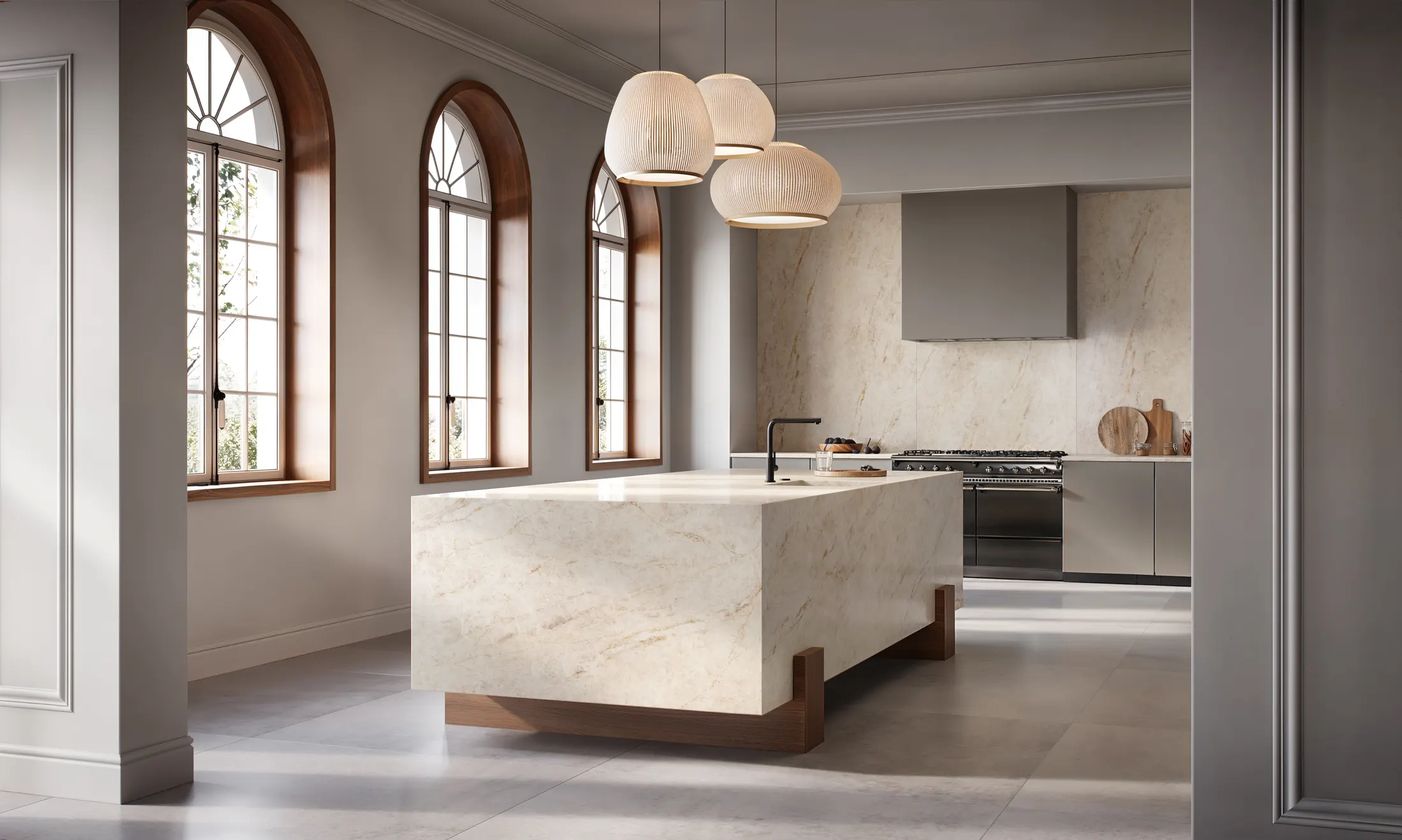 Kitchen island in pale stone beneath arched windows